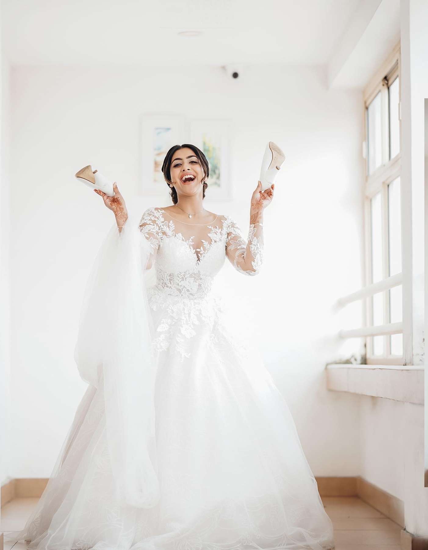 Joyful bride holding her wedding shoes